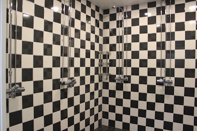 Monipuoliset suihkutilat erilaisilla kylpyhuonetarvikkeilla ja modernilla laatta-designilla.