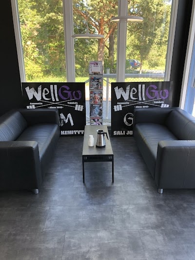 Moderni kuntosalihuone, kaksi mustaa sohvaa ja kahvipöytä, iso ikkuna ja ulkoilmailma näkyvissä, Finnish gym.