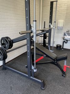 Kuntoiluvälineet ja painonnostopenkki kuntosalissa, valmiina harjoitteluun.