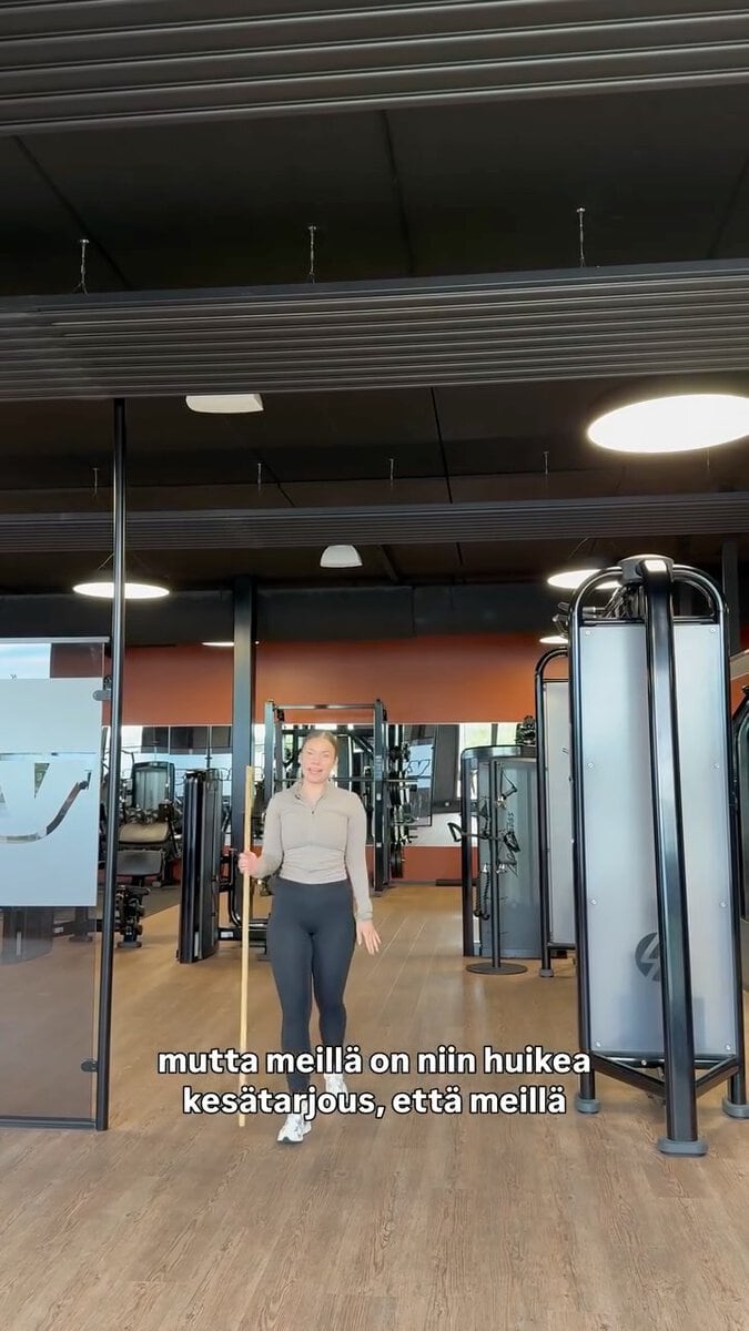 Nainen treenaa kuntosalilla, modernit laitteet taustalla.