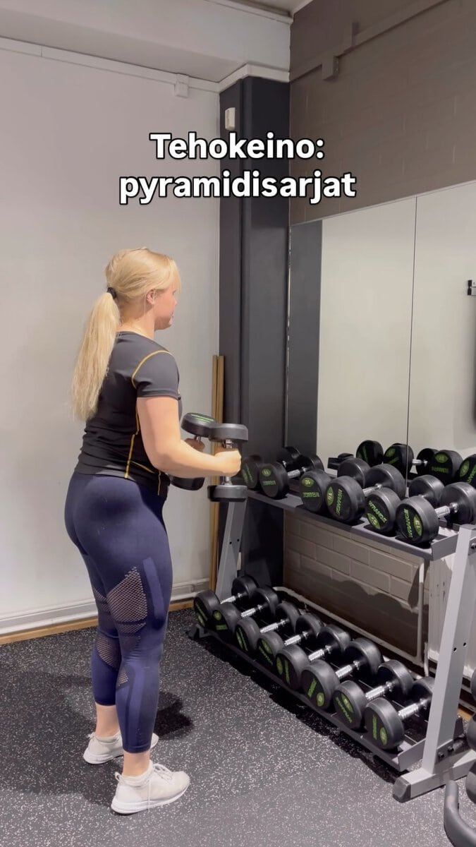 Nainen treenaa pyramidisarjoilla kuntosalilla.