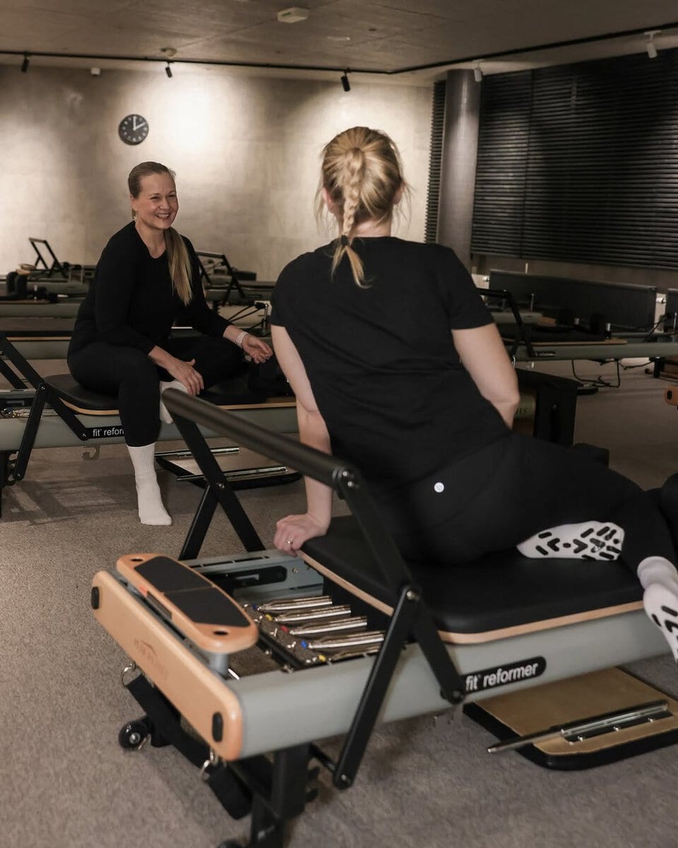 Kaksi naista harjoittelee pilates- tai fysioterapiatunnilla.