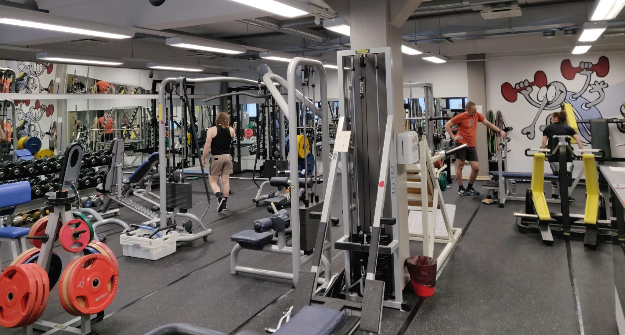 Kuntosalin sisäkuva, monipuolisia laitteita ja kuntosalilaisia.