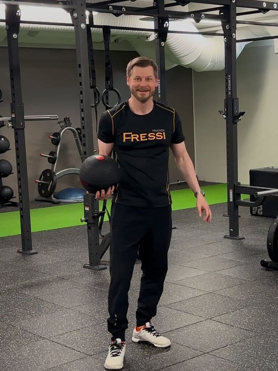 Henkilö treenaa kuntosalilla, pitää painonnostopalloa kädessään.